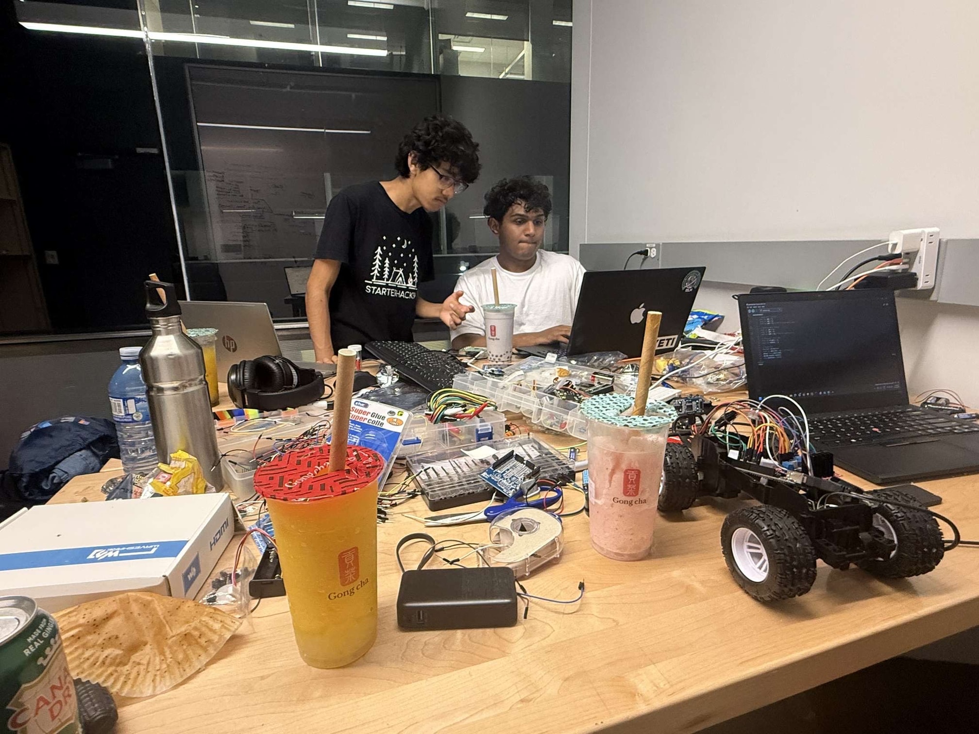 A photo of Vedant and a teammate building a robot late at night at a hackathon in Waterloo